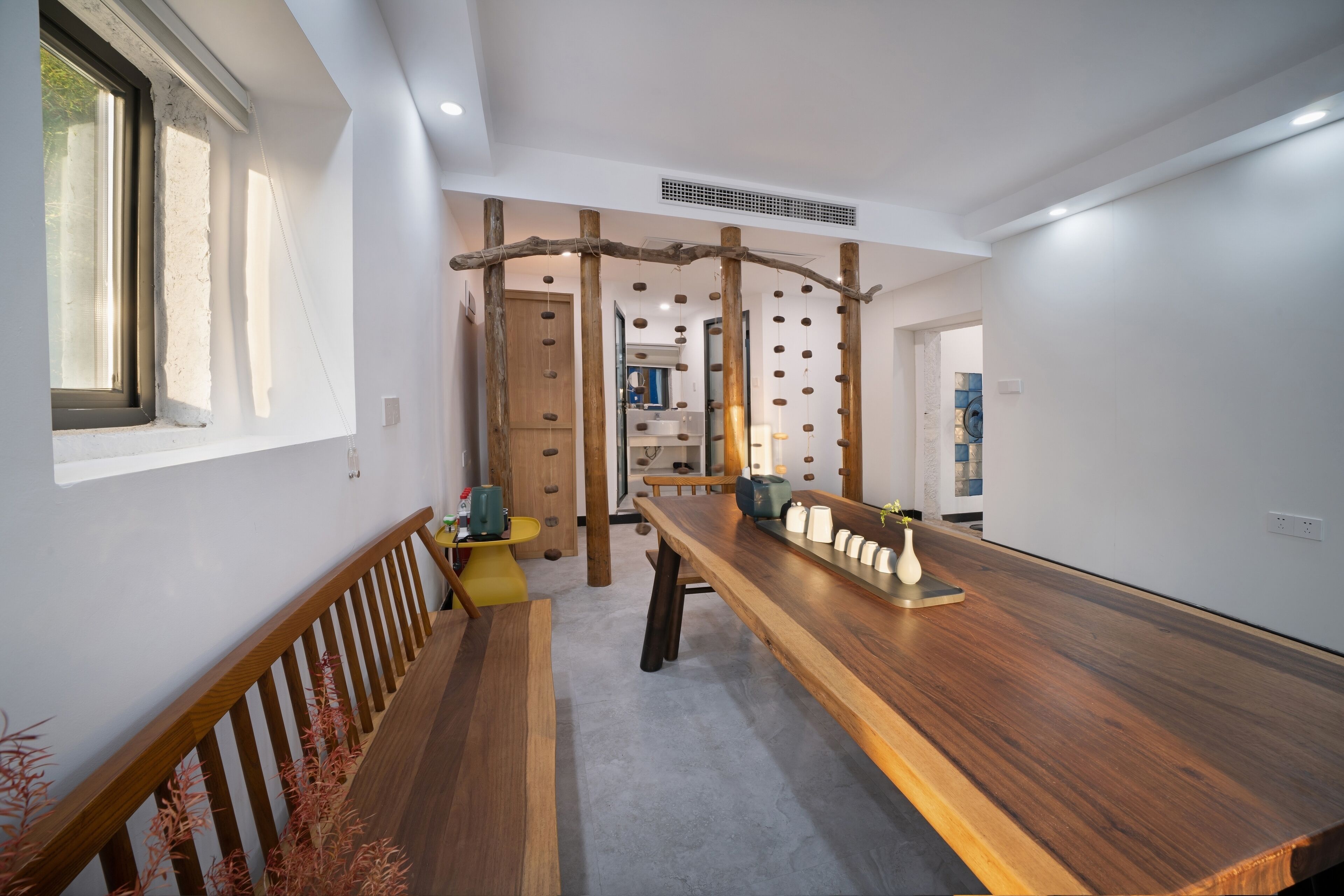 A modern kitchen with a wooden countertop, a hanging wooden rack, and a view of the adjacent bathroom.