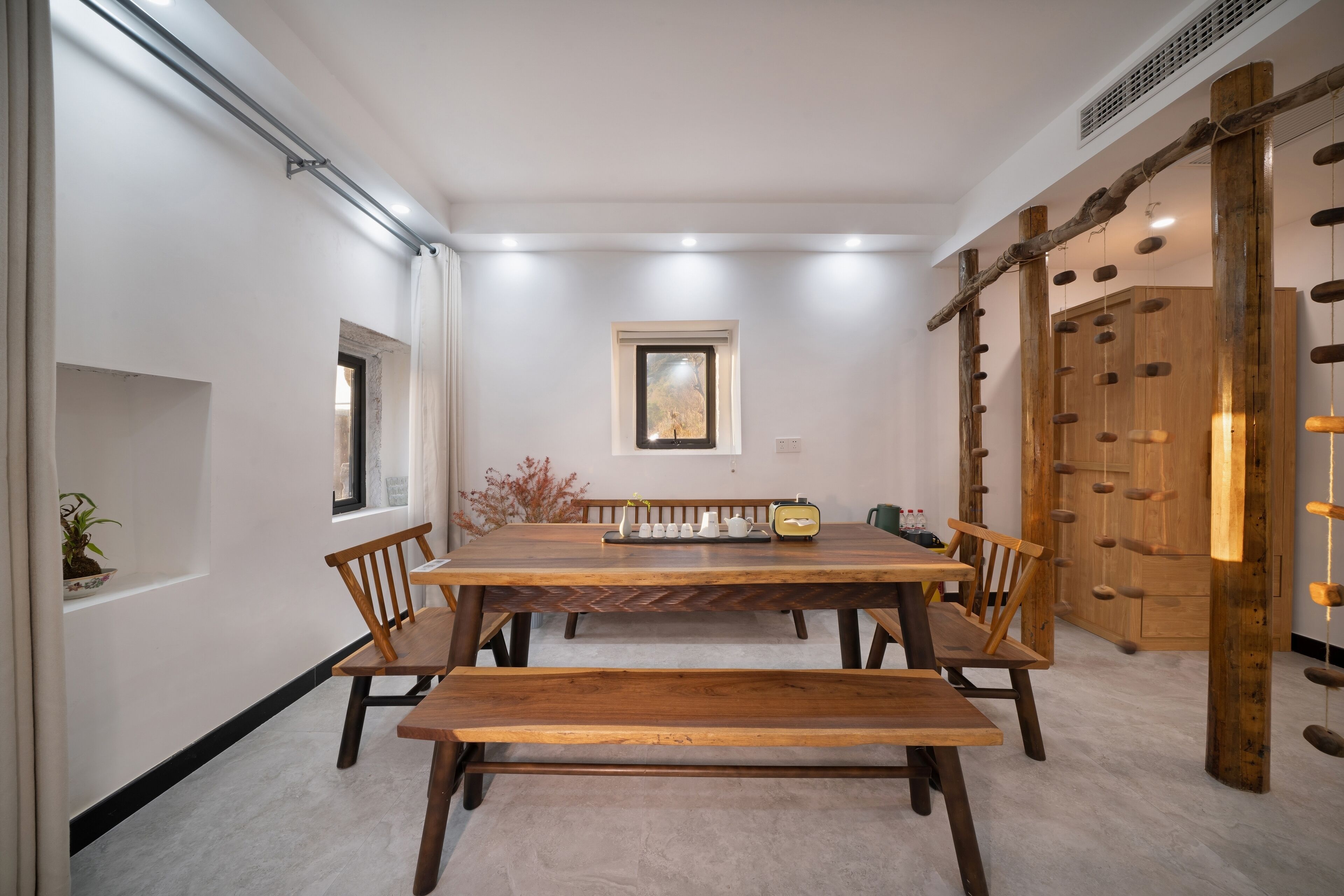 A dining area with a wooden table and benches, a window, and a wooden climbing wall.