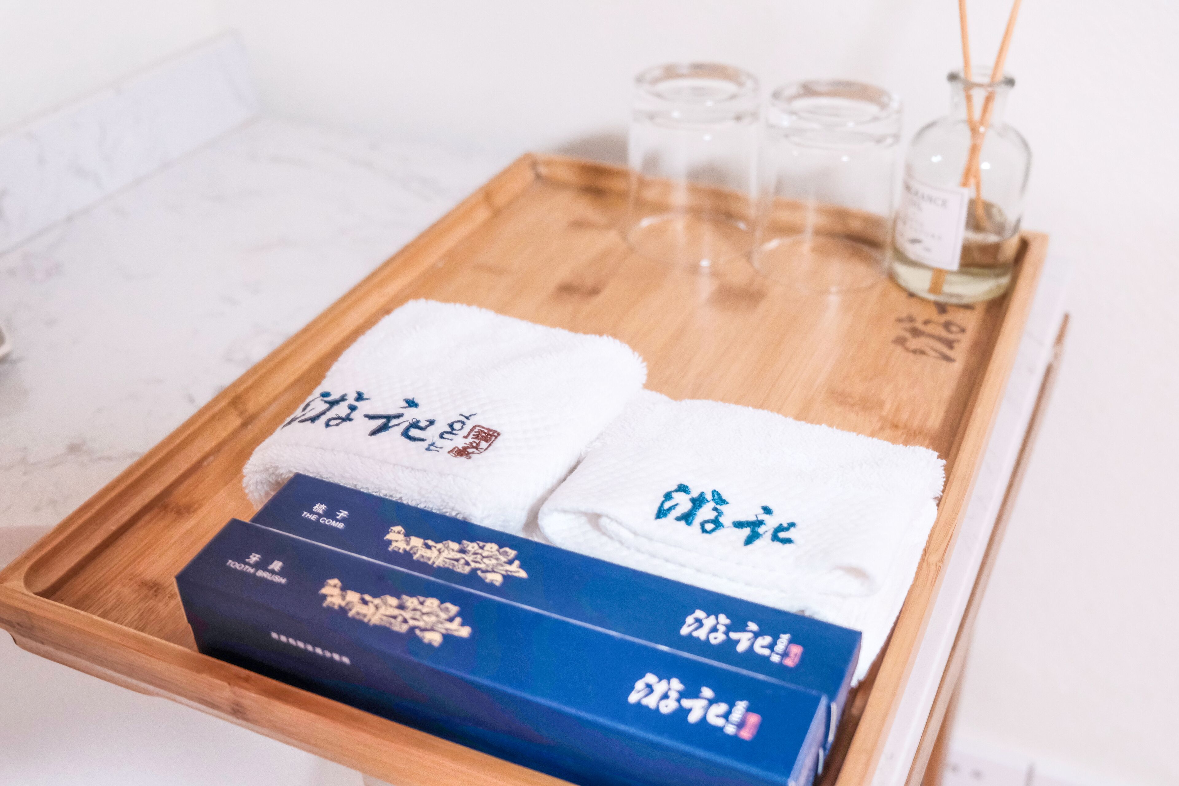 Un plateau en bois avec deux serviettes blanches et deux boîtes bleues, le tout posé sur une surface en marbre.