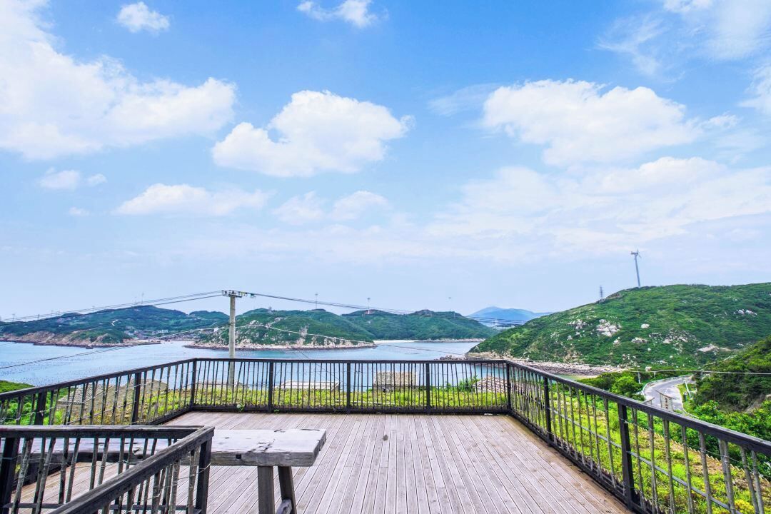 Una terraza de madera con barandilla que da a un río y colinas.