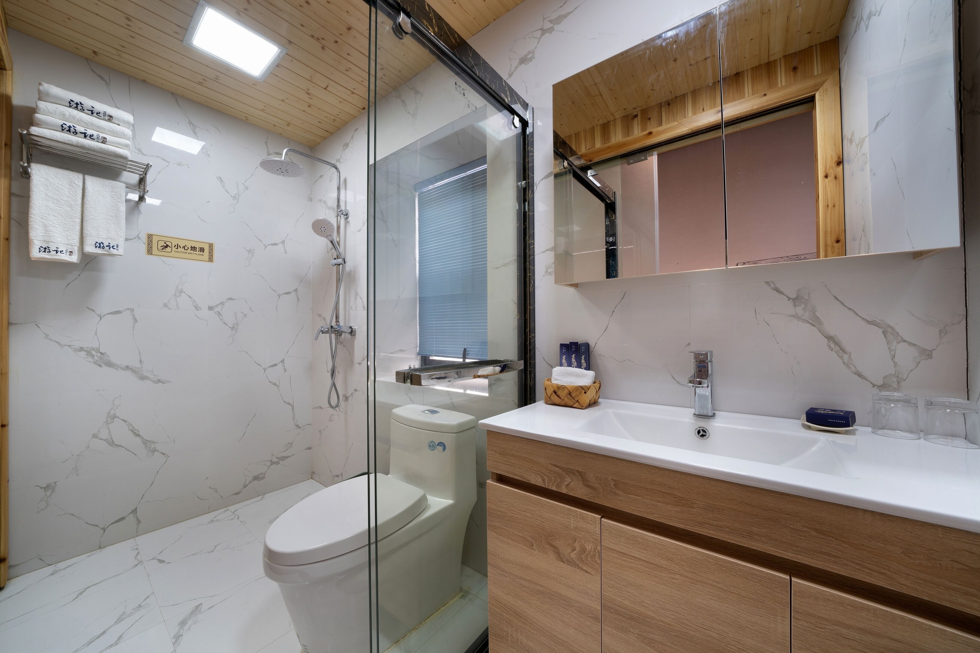 Une salle de bain moderne avec une douche à parois de verre, des toilettes, un meuble-lavabo avec un miroir et un porte-serviettes.