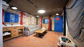 A room with a stone wall, a wooden table, a sofa, and a small play area with toys.