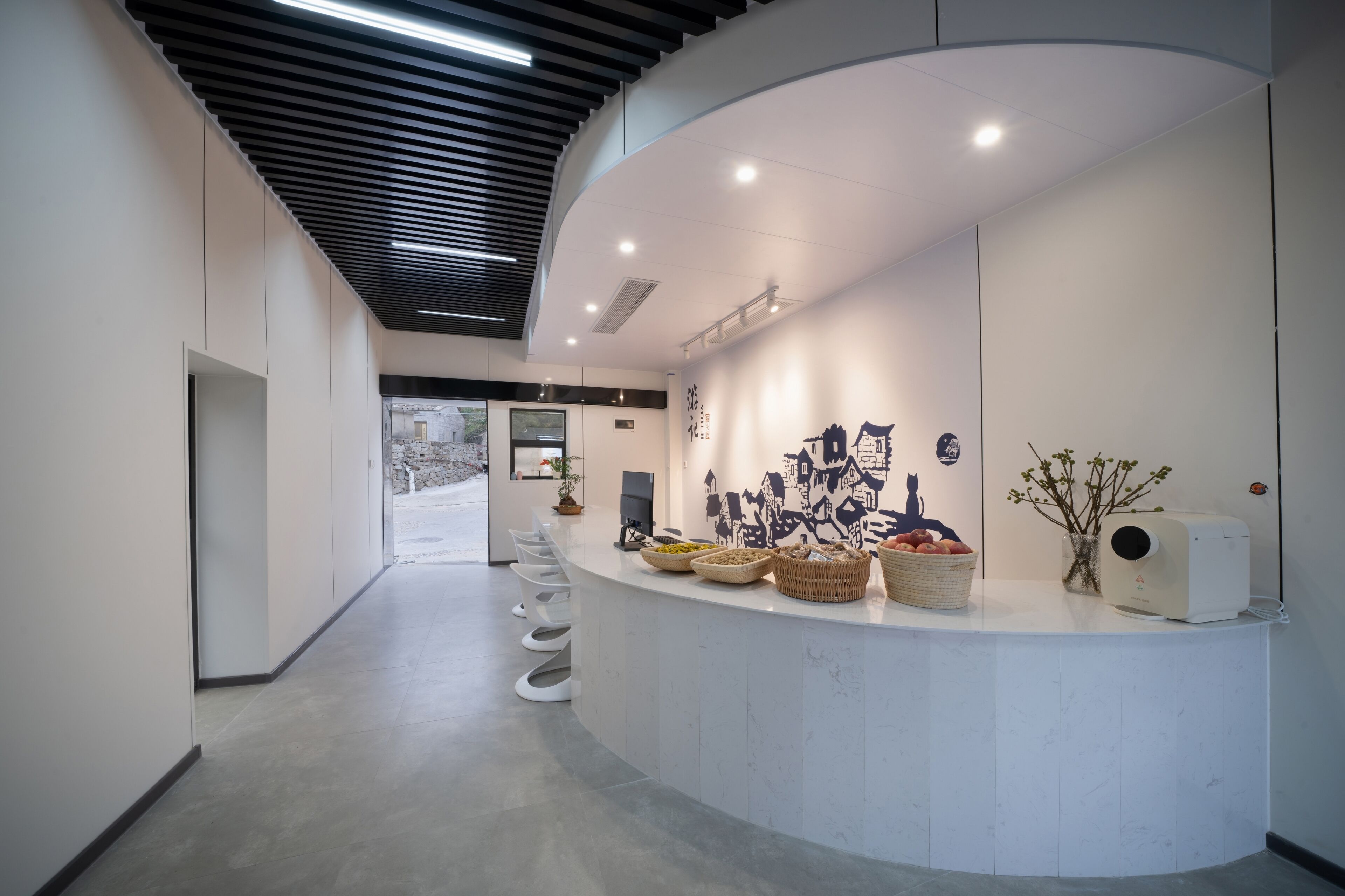 A modern reception area with a curved counter, baskets of fruits, and a wall-mounted air purifier.