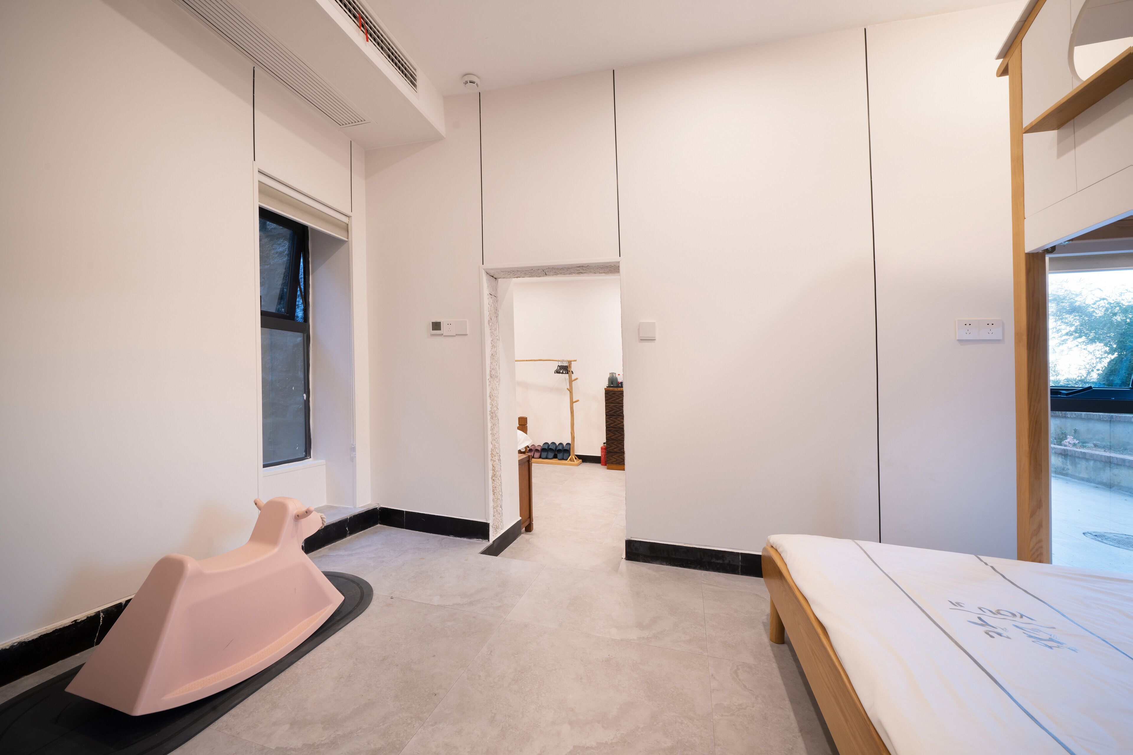 A modern hotel room with a large bed, a small seating area, and a view of the outdoors.
