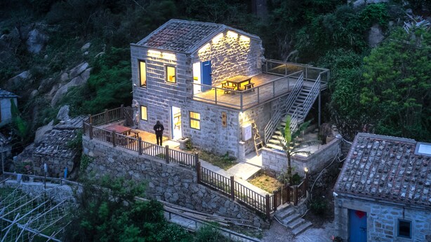Une maison en pierre dotée d’une terrasse et d’un escalier menant à un deuxième étage.