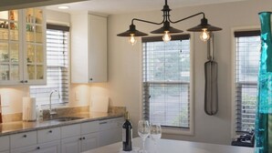 A modern kitchen with white cabinets, a granite countertop, and a central island with two stools.