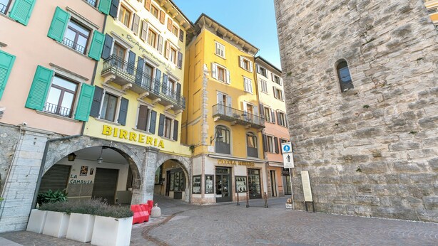 A cobblestone street with historic buildings, including a bakery named "BIRREARIA" and a pharmacy "PICCOLA MURANO". - The Harbor Old House, Riva del Garda, Italy (Riva del Garda)