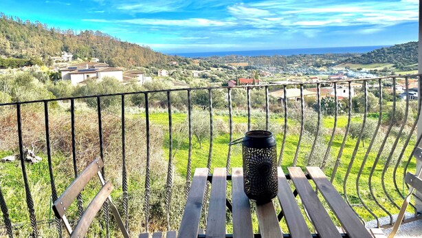 A balcony with a view of a coastal landscape, a metal railing, and a black lantern on a wooden table. - Maion Bellevue con Patio (Cardedu)