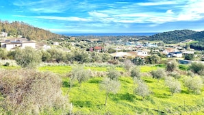 A coastal village with houses, green fields, and a clear blue sky. - Maion Bellevue con Patio (Cardedu)
