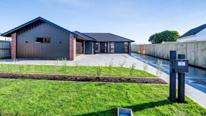 A modern building with a garage, a covered driveway, and a well-maintained lawn.