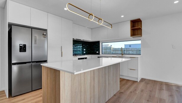 A modern kitchen with a central island, stainless steel appliances, and a view of the outside.