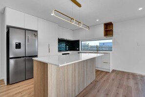 A modern kitchen with a central island, stainless steel appliances, and a view of the outside.