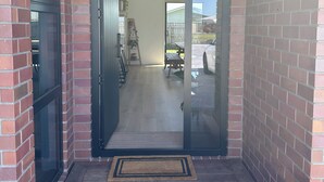 A modern entryway with a glass door, brick walls, and a wooden floor.