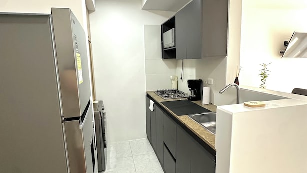 Una cucina moderna con frigorifero in acciaio inossidabile, piano cottura a gas e pensili grigio scuro.