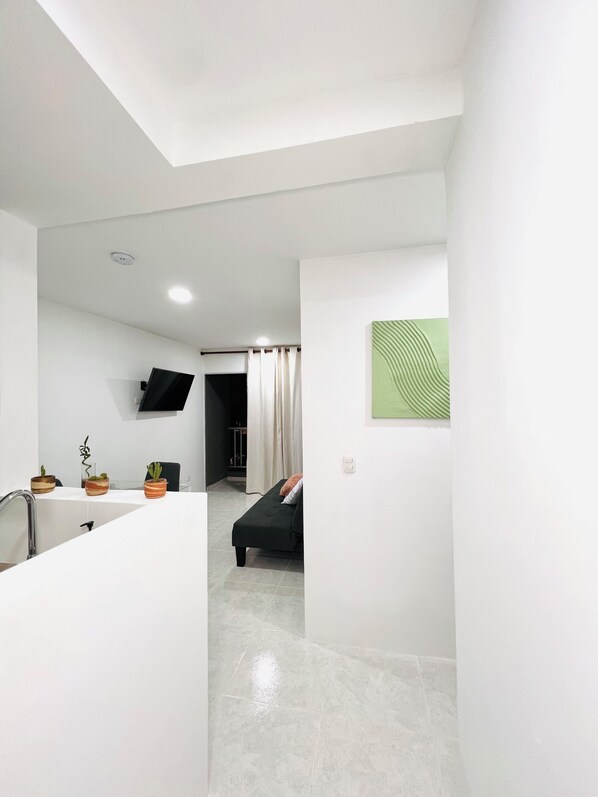 A modern, minimalist living space with a kitchen area, a dining table, and a sofa. - Just a few minutes from the beach with a beautiful view from the balcony, enjoy! (Cartagena de Indias)