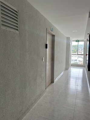 A hallway with a textured wall, a door with a sign, and a view through a window. - Just a few minutes from the beach with a beautiful view from the balcony, enjoy! (Cartagena de Indias)