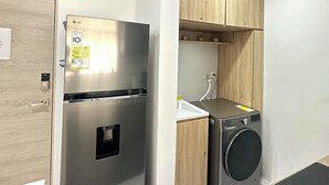 Una cucina compatta con frigorifero in acciaio inossidabile, lavatrice integrata e mobili in legno.