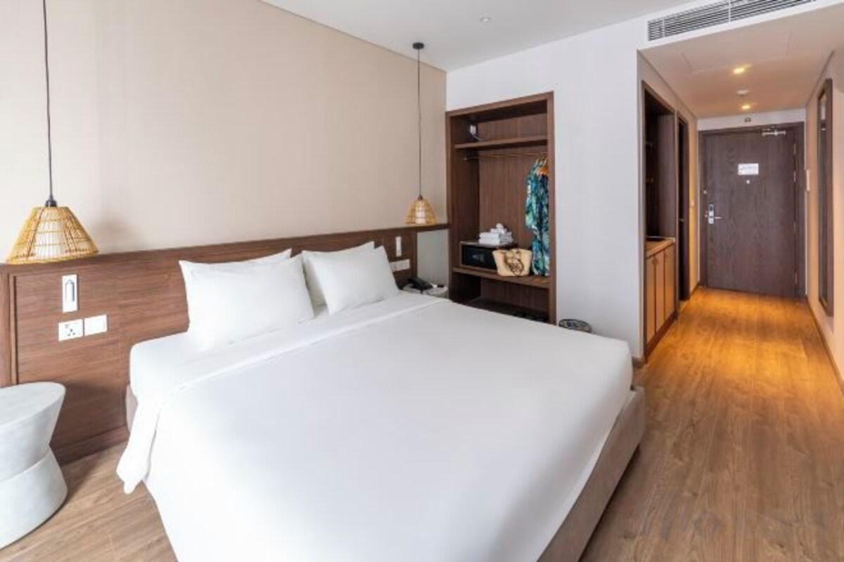 Une chambre d’hôtel avec un grand lit, une table de chevet et une armoire.