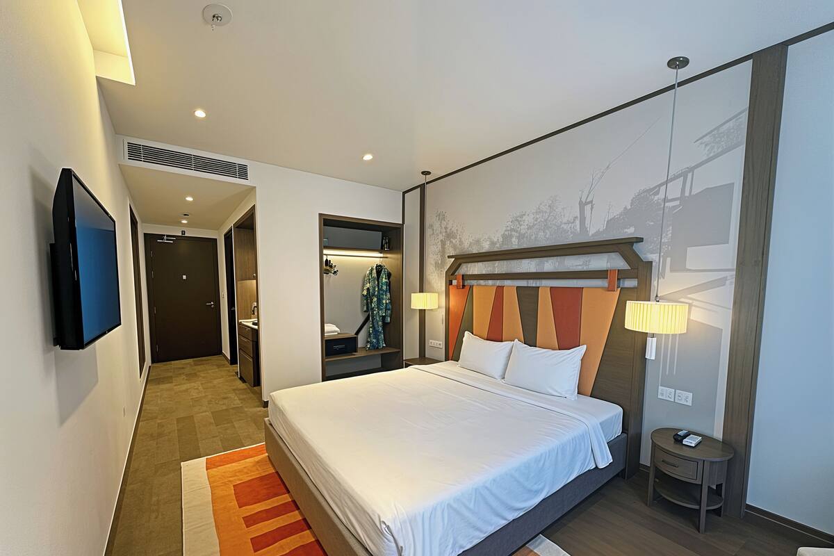 A hotel room with a bed, a TV, a desk, and a bathroom.