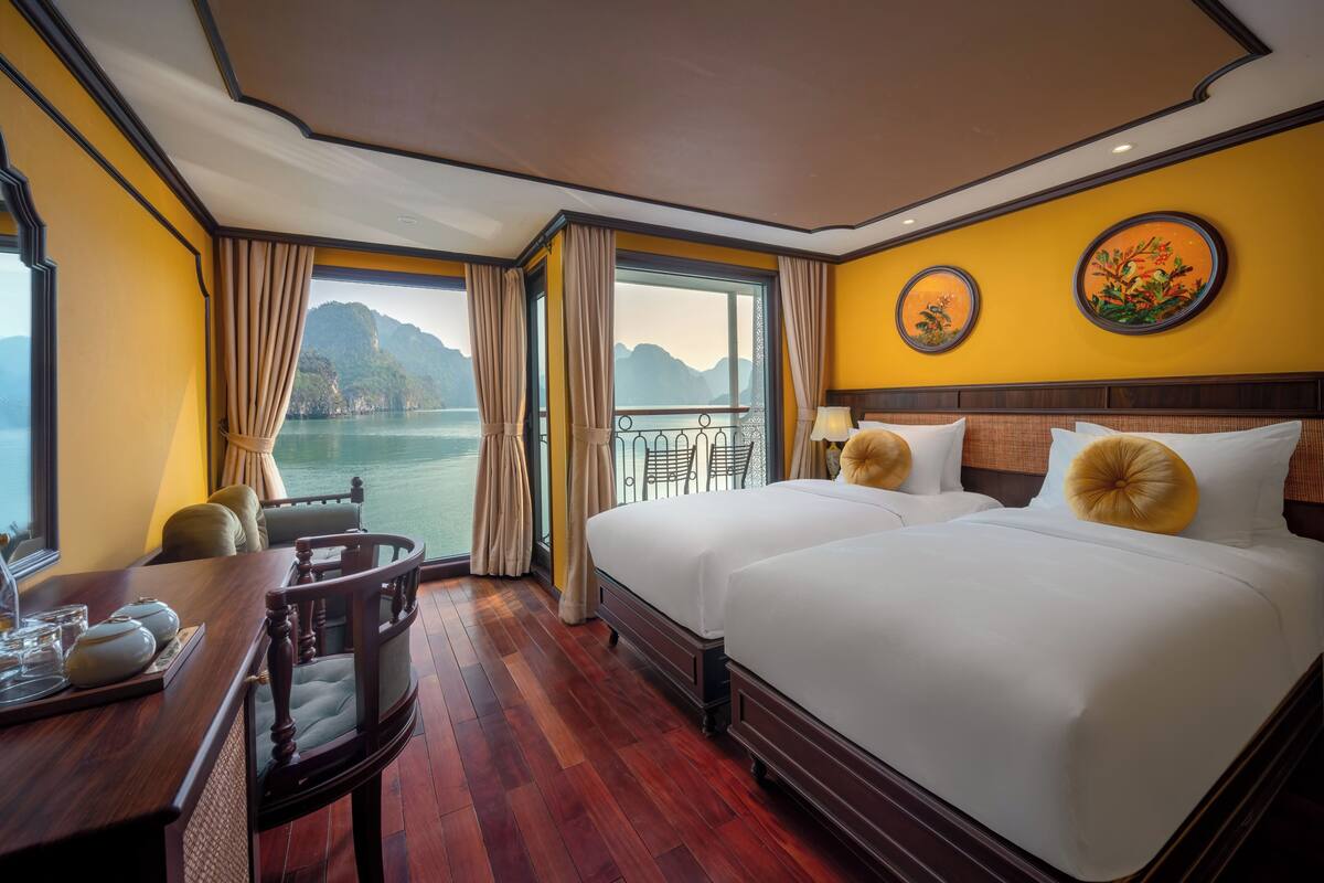 Quarto de hotel com uma cama grande, uma mesa com cadeira, vista para o mar e varanda.