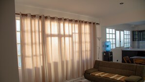 A living room with a sofa, a water dispenser, and a kitchen area in the background. - Enjoyable 2-bedroom apartment with WiFi in Uyuni (Uyuni)