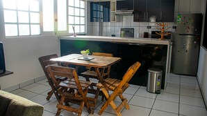 A kitchen with a dining table, chairs, a trash bin, a refrigerator, and a window with blinds. - Enjoyable 2-bedroom apartment with WiFi in Uyuni (Uyuni)