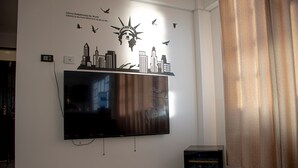 A flat-screen TV mounted on a white wall with a cityscape mural above it. - Enjoyable 2-bedroom apartment with WiFi in Uyuni (Uyuni)