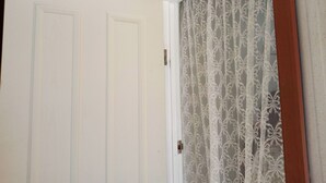 A white door with a metal handle, a lace curtain, and a wooden trim. - Cozy sleep out  with free wi-fi (Kennington)