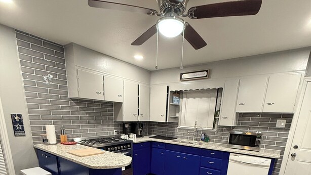 A modern kitchen with a central island, white cabinets, and a blue accent wall. - Peaceful Arlington Home (Arlington)