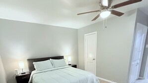 A bedroom with a bed, nightstands, a ceiling fan, and a door. - Peaceful Arlington Home (Arlington)