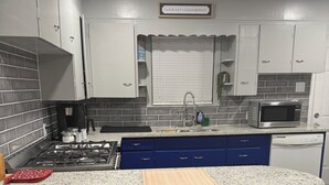 A kitchen with a granite countertop, a gas stove, a microwave, and a sink. - Peaceful Arlington Home (Arlington)