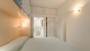 Ein Schlafzimmer mit einem Bett, einem Kleiderschrank, einer Tür und einer Wandleuchte.