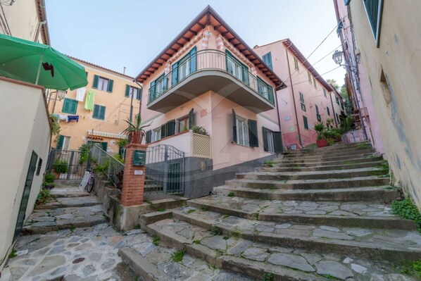 A narrow stone staircase leading to a building with a balcony. - APPARTAMENTI MALAGA - BILO MALAGA PIANO TERRA (Porto Azzurro)