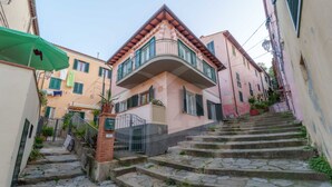 Un escalier étroit en pierre menant à un bâtiment doté d’un balcon.