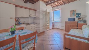Una cocina compacta con muebles blancos y una zona de comedor con mesa y sillas.