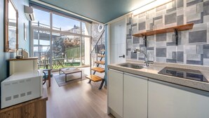 A modern kitchen with a large window, a built-in stove, and a wooden dining area. - Yeosu Island Pet Pension (Yeosu)