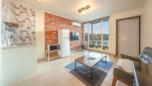 A modern apartment with a kitchen, dining area, and a large window offering a scenic view. - Yeosu Island Pet Pension (Yeosu)