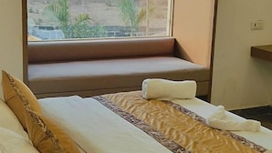 Una habitación de hotel con una cama, un ventanal con vistas al exterior y un equipo de aire acondicionado sobre la ventana.