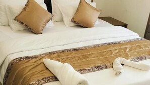 Una cama bien hecha con ropa de cama blanca y marrón, un cabecero y dos almohadas.