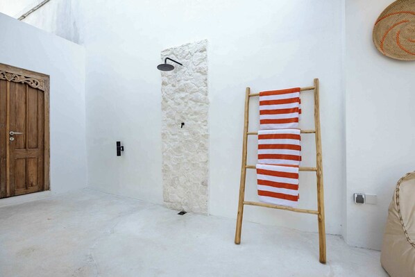 Un pasillo estrecho con una puerta de madera, una pared de piedra y una escalera de madera con una toalla a rayas.