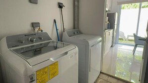 A laundry room with two washing machines, a drying machine, and a utility sink.