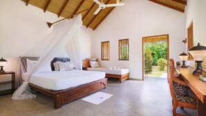 A bedroom with a canopy bed, a smaller bed, a desk with a chair, and a ceiling fan. - Happy Man Village (Kosgoda)