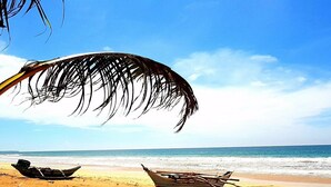 A beach with two boats and a large piece of fabric on the sand. - Happy Man Village (Kosgoda)