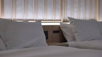 A hotel room with a bed, a nightstand, and a window with vertical blinds.