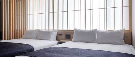 Habitación de hotel con dos camas, un separador de madera y ventanas amplias.