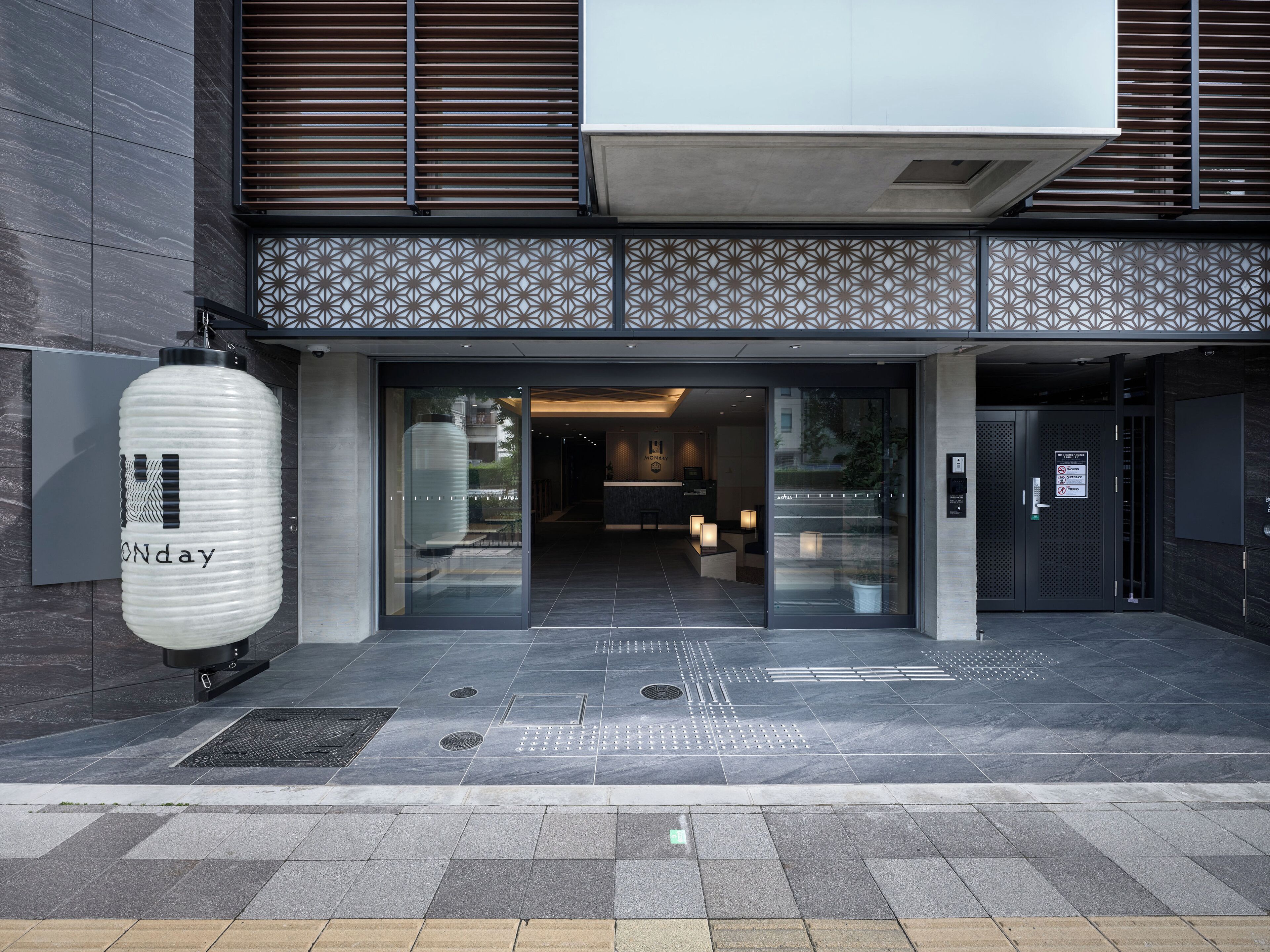 A modern building entrance with a glass door, a large decorative sign, and a visible reception area.