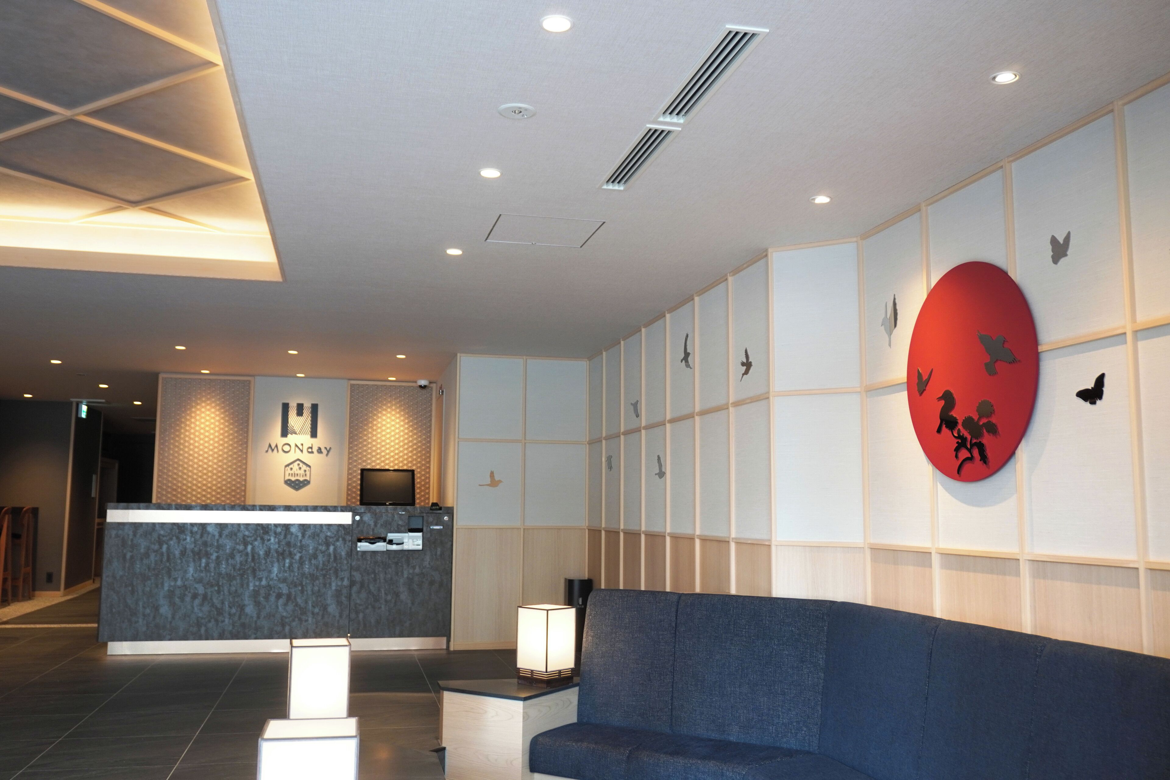 Un área de recepción con diseño moderno, que incluye un mostrador de recepción, zona de estar y detalles decorativos en la pared.