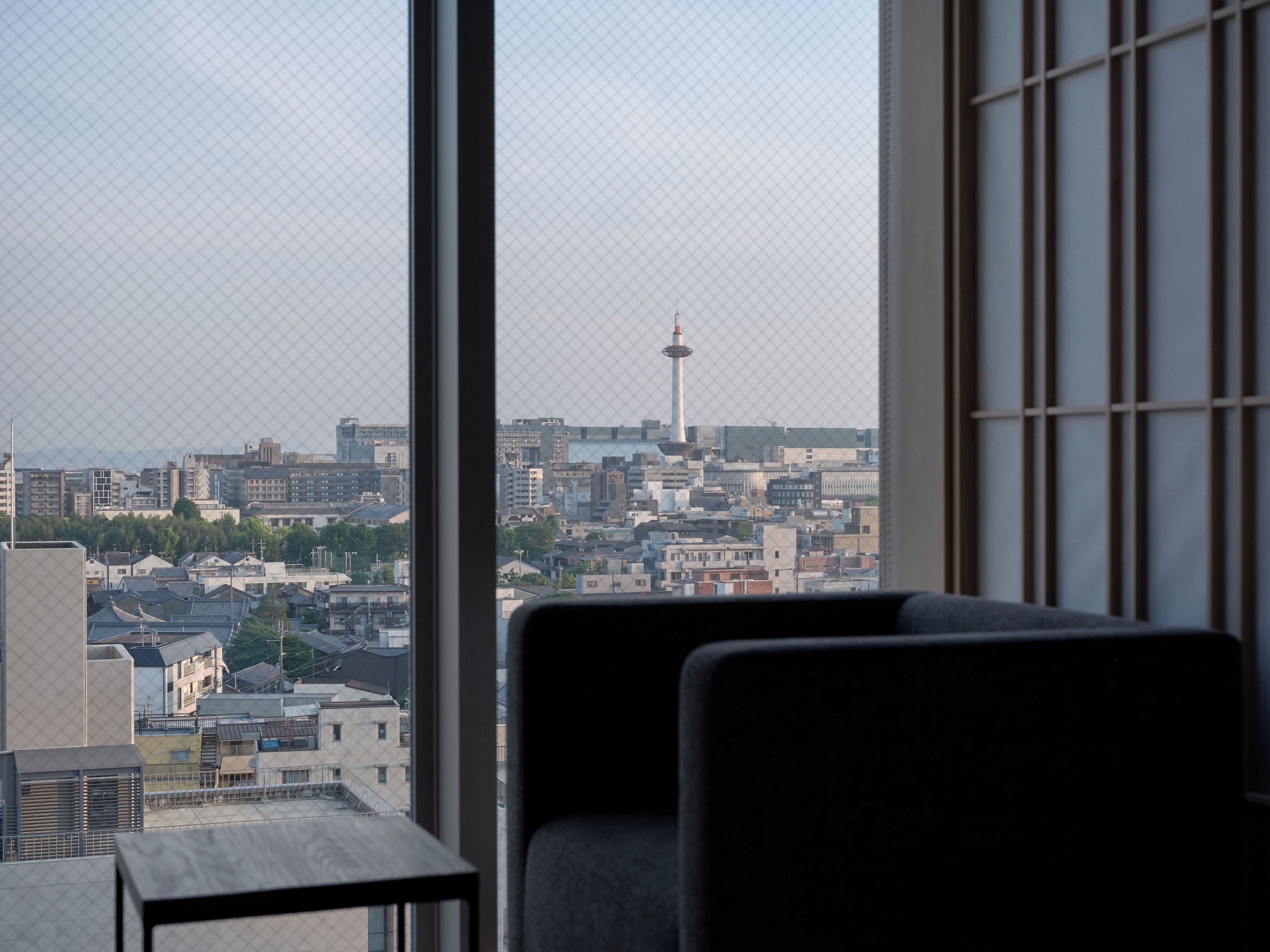 Una habitación con un ventanal grande que da a un paisaje urbano, destacando una torre imponente y varios edificios.