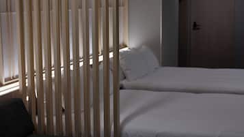 Een hotelkamer met twee bedden, een houten scheidingswand en een bank.