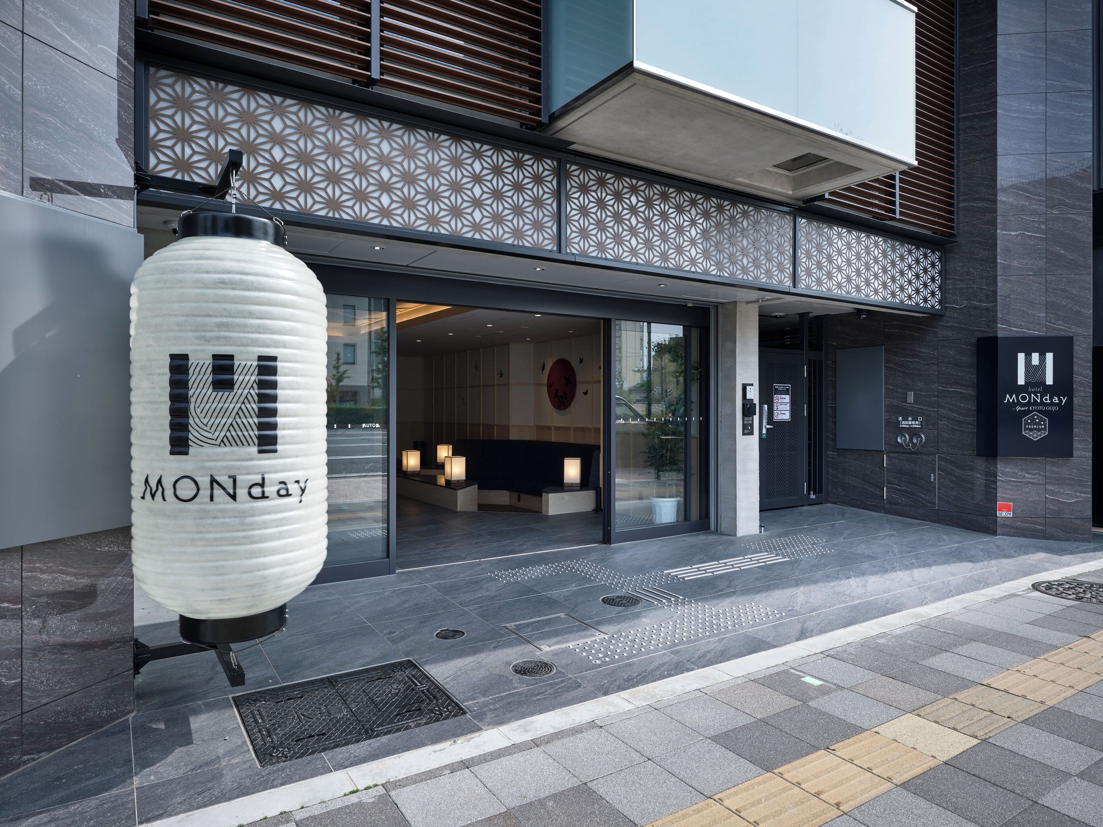 A modern hotel entrance with a reception desk, a waiting area, and a sign indicating "MONDAY" and "Hotel MONDAY."
